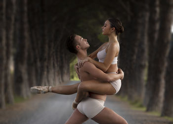 Couple dancing in road amidst tree