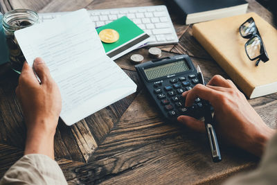 Midsection of businessman using calculator on table 