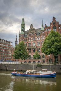 Buildings by river against sky in city