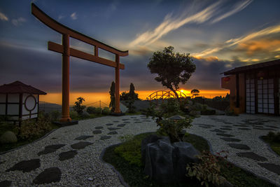 House by trees against sky at sunset