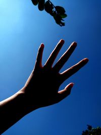 Low angle view of hand against clear blue sky
