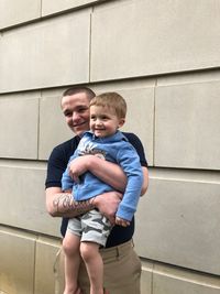 Teenage boy carrying brother against wall