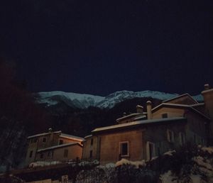 Houses by mountain against sky at night