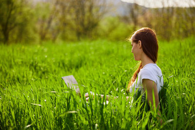 Side view of woman standing amidst plants on field