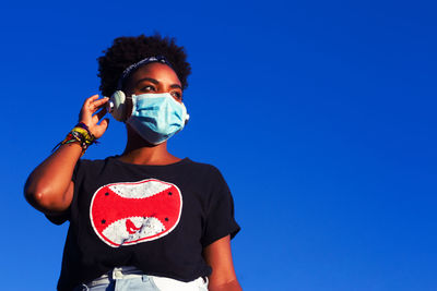 Low angle portrait of man standing against blue sky