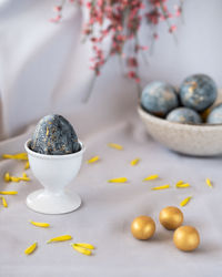 Blue egg in a white egg stand, easter concept with small golden eggs. vertical photo.