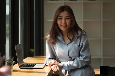 Young woman using phone while sitting on table