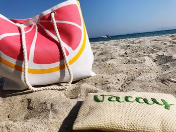 Close-up of bags on sand at beach against clear sky