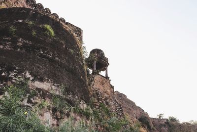 Low angle view of rocks on cliff against clear sky