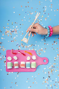 Female hand using chopsticks with candy sushi