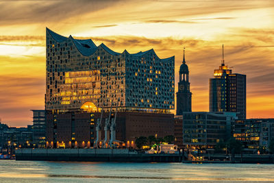 View of modern buildings at waterfront during sunset