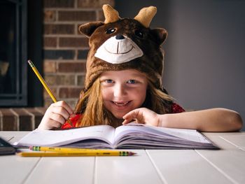 Portrait of smiling girl drawing in book while sitting at desk