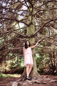 Portrait of smiling young woman standing on tree