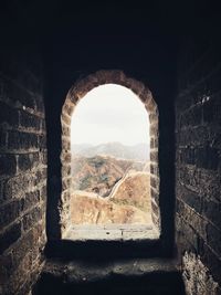 Archway of old building against sky seen through arch window