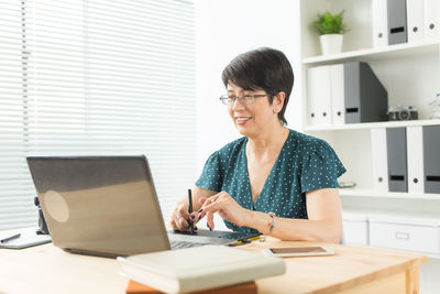 Woman using phone while sitting on table