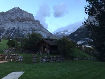 Houses on field by mountains against sky