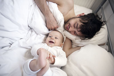 Father with baby son in bed, london, united kingdom