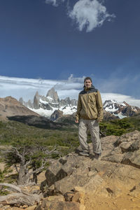 Rear view of man standing on mountain against sky