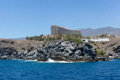 Sea by buildings against clear blue sky