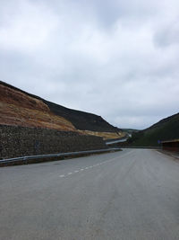 Empty road by mountain against sky