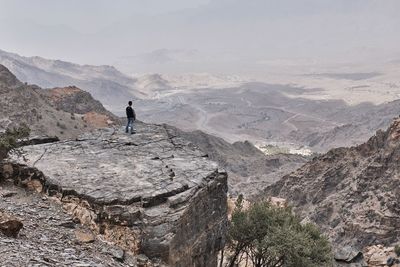 Man walking on rocks against mountains