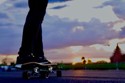 Low section of person skateboarding on skateboard against sky