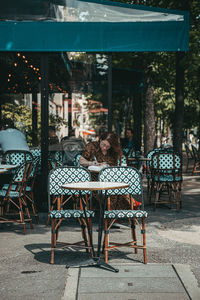 Chairs and tables at sidewalk cafe in city