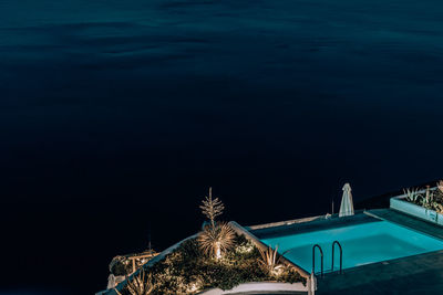 High angle view of illuminated building by sea against sky at night