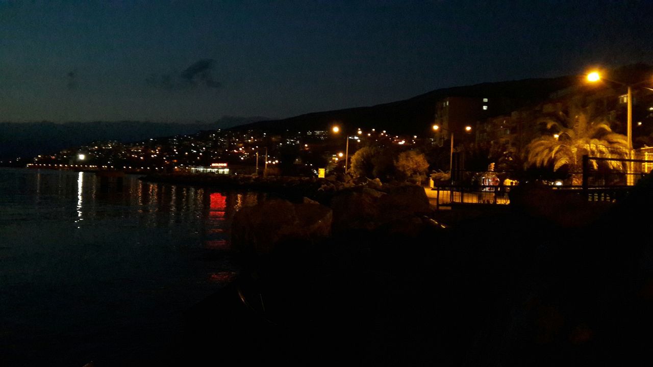 illuminated, night, water, reflection, sea, architecture, built structure, river, waterfront, building exterior, clear sky, city, copy space, lighting equipment, sky, street light, dark, dusk, outdoors, light - natural phenomenon