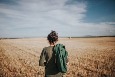 Rear view of woman standing in wheat field against sky