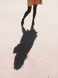 Low section of woman standing on sand during sunny day