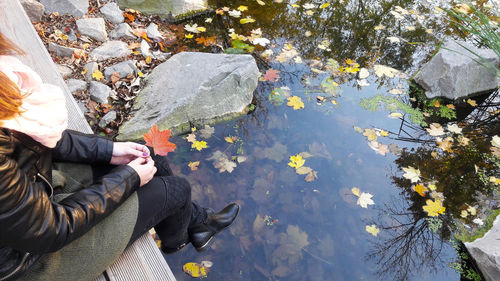 Low section of woman sitting by pond