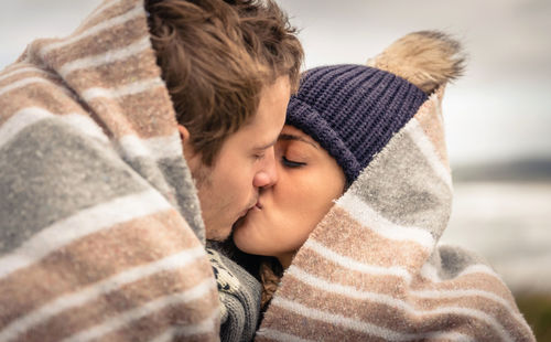 Couple covered with blanket kissing