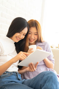 Young woman using smart phone while sitting on laptop