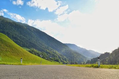 Scenic view of road by mountains against sky