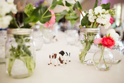 Flowers in jars by figurines on table