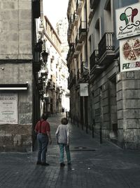 Rear view of people walking on street amidst buildings