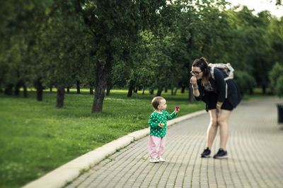 Mother talking with daughter while standing on footpath at park
