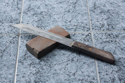 Close-up of knife and whetstone on tiled floor