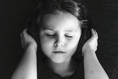 Close-up of cute girl wearing headphones by wall