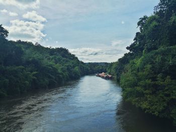 River amidst trees in forest against sky