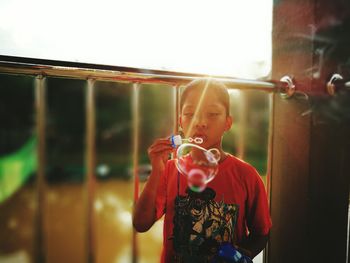 Boy playing with bubbles by railing