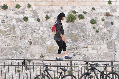 Full length side view of woman against wall