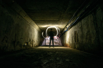 Rear view of man in illuminated tunnel