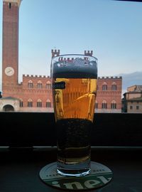 Beer glass on table against building