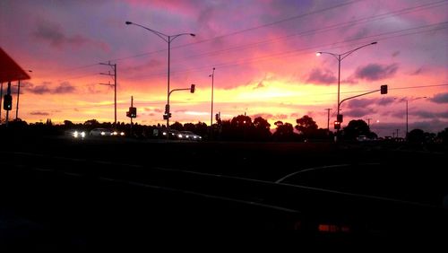 Silhouette of road against cloudy sky at sunset