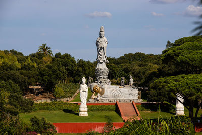 Statue in park against cloudy sky