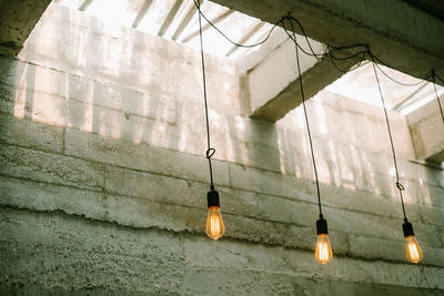 Low angle view of illuminated light bulbs hanging on wall