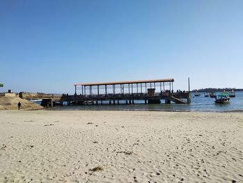 Pier on beach against clear sky