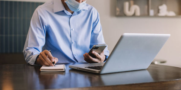 Midsection of woman using laptop at table